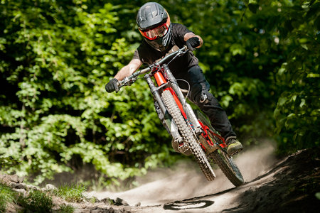 Mountainbiker rides in forest on one wheel