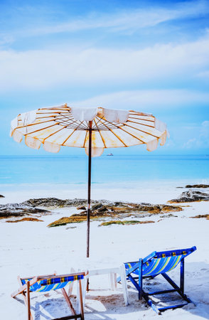Beach chair and umbrella on the white sand beach with blue skyの写真素材