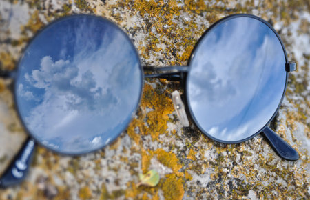 A cloud is reflected in sunglasses on a stone の写真素材