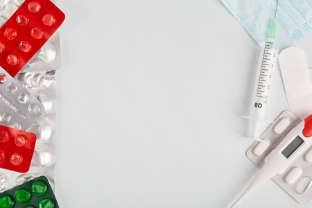 Facial protective mask thermometer  and pills. Pills on a white background concept. Flat lay and copy spaceの写真素材