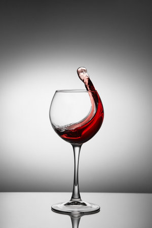 Glass with a splash of red wine on white background. Splashing red wine in a glassのeditorial素材