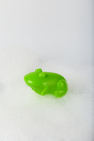 Minimalistic concept toy frog in the foam. bathing childrenの写真素材