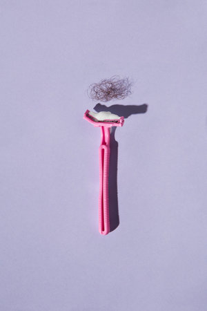 Broken woman pink plastic razor on colorful background. Before and after concept. Removal of unwanted hair. Big hair problemの写真素材