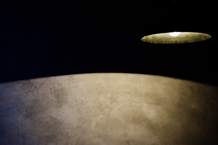 Abstract minimalist lighting design with a single lamp illuminating a textured concrete wall in the...