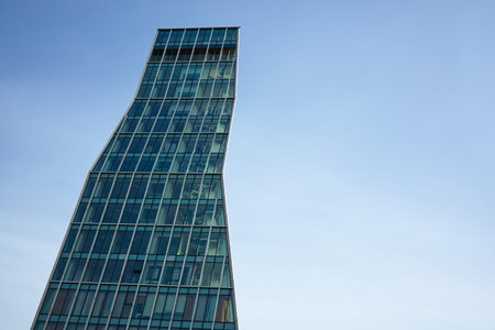 A professional shot of a modern skyscraper featuring a unique twisted or leaning architectural form....