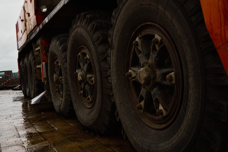A professional low-angle photograph focusing on the massive multi-axle wheels of an industrial...
