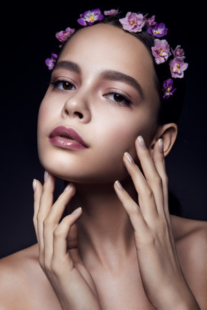 Beautiful girl with violet flowers. Clean skin.の写真素材