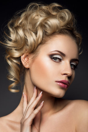 Glamour portrait of beautiful woman model with fresh daily makeup and romantic wavy hairstyle. Fashion shiny highlighter on skin, sexy gloss lips make-up and dark eyebrowsの写真素材