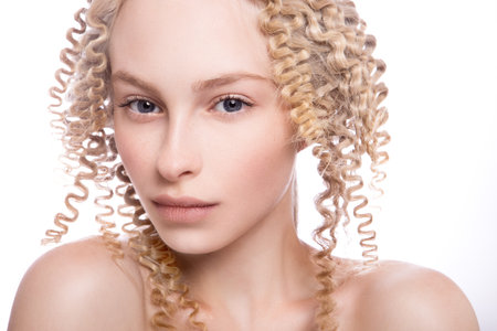 Portrait of a beautiful woman with curly blonde hair on white backgroundの写真素材