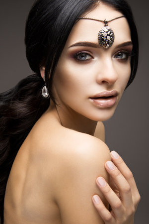 Beautiful model brunette with long curled hair. Bright makeupの写真素材