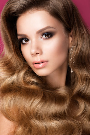 Beautiful young woman with long curly hair and bright make upの写真素材
