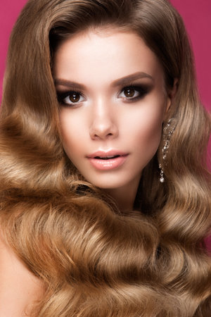 Beautiful young woman with long curly hair and bright make upの写真素材
