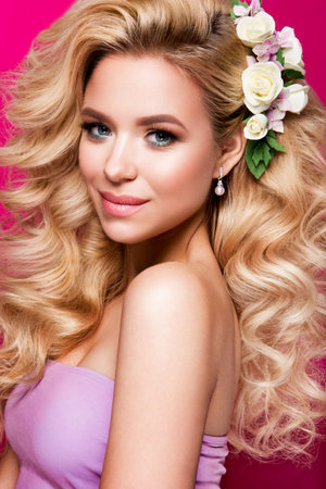 Beautiful young woman with long hair posing on pink shiny background. Healthy skin and long smooth hair. Pink lipsの写真素材
