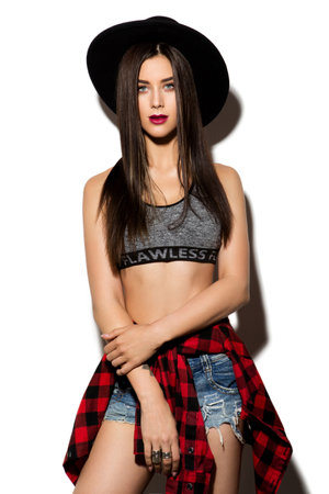 Beautiful young woman with long hair posing on wight background. Black hat.の写真素材