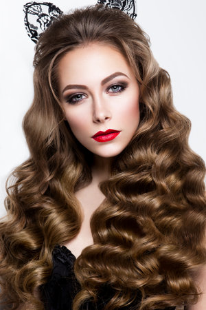 Glamour portrait of beautiful girl model with makeup and romantic wavy hairstyle. Fashion shiny highlighter on skin, sexy gloss lips make-up and dark eyebrows.の写真素材