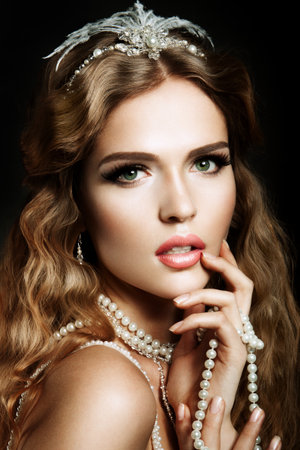 Glamour portrait of beautiful girl model with makeup and romantic wavy hairstyle. Fashion shiny highlighter on skin, sexy gloss lips make-up and dark eyebrows.の写真素材