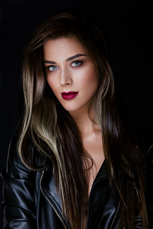 Glamour portrait of beautiful girl model with makeup and romantic wavy hairstyle. Fashion shiny highlighter on skin, sexy gloss lips make-up and dark eyebrows.の写真素材