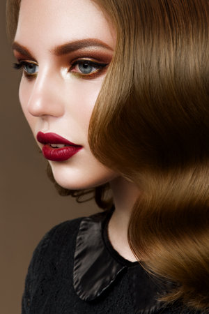 Glamour portrait of beautiful woman model with fresh daily makeup and romantic wavy hairstyle. Fashion shiny highlighter on skin, sexy gloss lips make-up and dark eyebrowsの写真素材