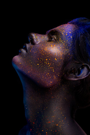 Glowing neon makeup with dramatic look in his eyes. Creative body art on the theme of space and stars. Amazing close-up portrait glow in the dark makeup.の写真素材