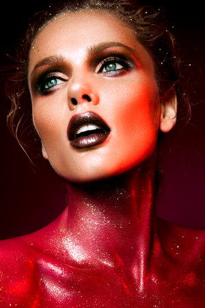 Beautiful woman with red make up and glitter on the neck and hair