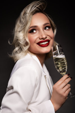 Close up portrait of pretty blond female handling prosecco. Beautiful makeup with red lips.の写真素材