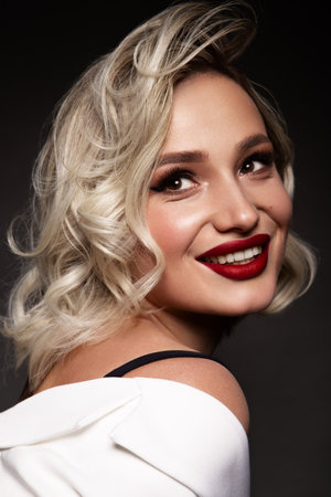 Close up portrait of pretty blond female. Beautiful makeup with red lips.の写真素材