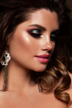 Glamour portrait of beautiful girl model with makeup and romantic hairstyle. Fashion shiny highlighter on skin, gloss lips make-up and dark eyebrows. Pink lipsの写真素材