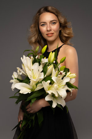 Beautiful young woman holds a lily flower in her hand. The concept of youth and healthの写真素材