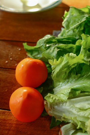 Red tomatoes and green lettuce on a wooden table. Useful vegetables. Healthy lifestyle. Selective focus.の写真素材
