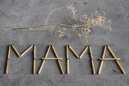 Abstract background of concrete and matches. Against the backdrop of matches laid out the word "mother", and is a sprig of dried flowers on top of the letters. World Day of the Mother. International day of the Mother. World Day Mom.の写真素材