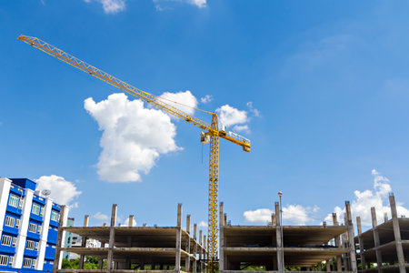 Tall buildings under construction with cranes against a blue sky