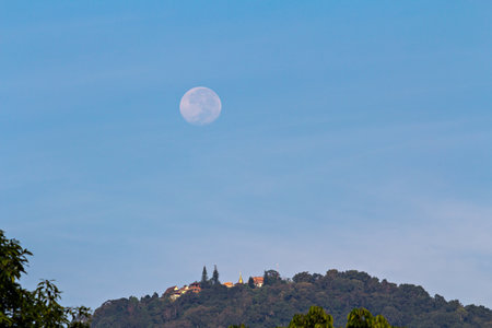 Full moon setting over Buddhist temple on mountainの写真素材
