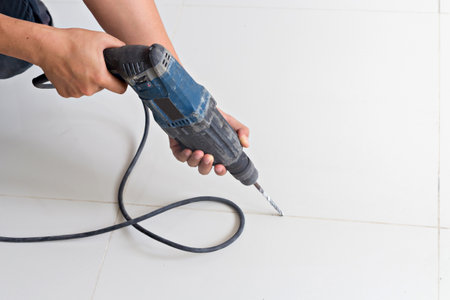 Man hands hold electric drill on the floorの写真素材