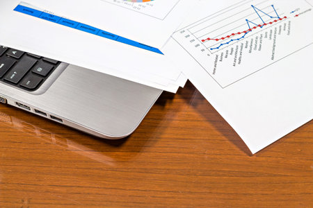 Laptop and report paper on vintage office wooden deskの写真素材