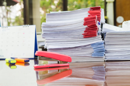 Stapler with pens and business documents stack on table