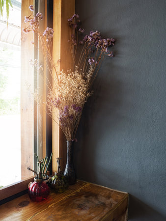 Dried flowers in vase on table beside windowsill, vintage toneの写真素材