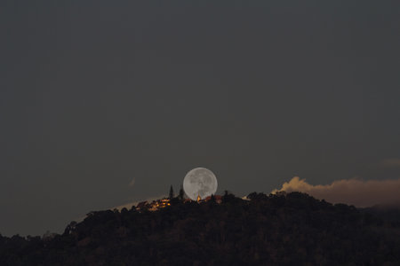 Supermoon setting over Buddhist temple on mountain at early morning, focus at templeの写真素材