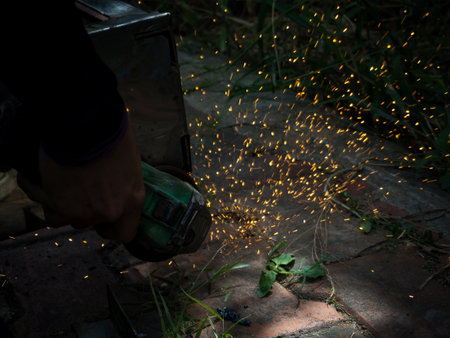 Close-up of worker cutting metal with grinder. Sparks while grinding iron.
