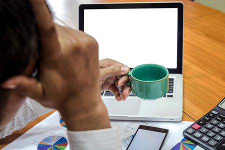 Businessman holding a cup of coffee and working on his plan projectの写真素材
