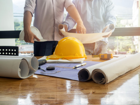 Blueprint on desk with architect and engineer backgroundの写真素材