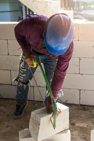 construction worker using saw for cutting foam bricksの写真素材