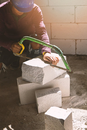 construction worker using saw for cutting foam bricksの写真素材