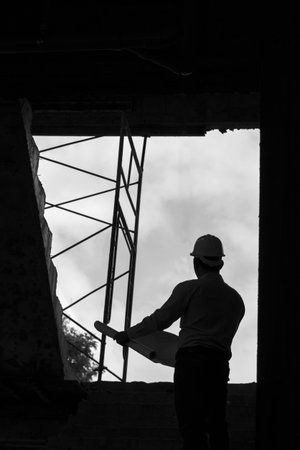 Monochrome image of Engineer with blueprint in building construction siteの写真素材