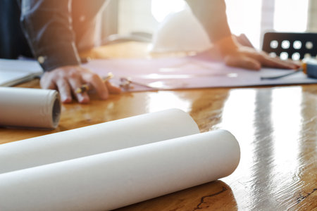 Blueprint on wooden desk with architect backgroundの写真素材