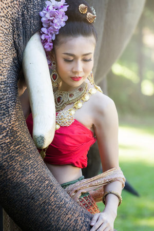 Pretty girl in traditional thai costumes touching elephant's trunkの写真素材