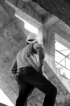 Monochrome image of Engineer with blueprint in building construction siteの写真素材