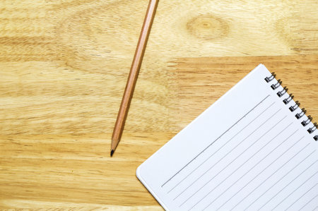 Notebook and pencil on wooden table, top view shotの写真素材