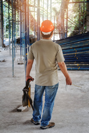 Worker holding tool bag in building construction siteの写真素材