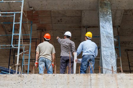 Engineer, foreman and worker discussing in building construction site