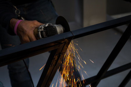 Close-up of worker cutting metal with grinder. Sparks while grinding iron.の写真素材